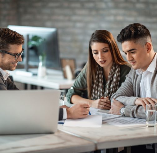 Young couple and bank manager reading financial reports while having a meeting in the office.